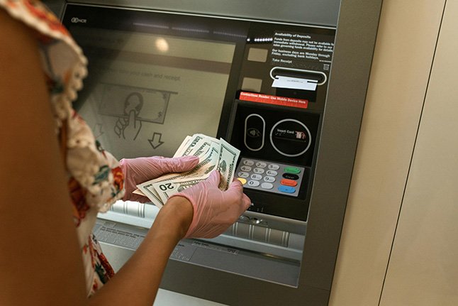 a person holding money in their hands at an ATM Machine